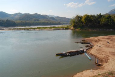 Mekong Nehri yakınındaki Luang Prabang, Laos akşamları kumlu plajda bağlı geleneksel uzun tekneler ile göster. 