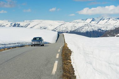 Aurland, Norveç - 08 Haziran 2012: Kimliği belirsiz kişi sürücü Bjorgavegen dağ karayoluyla Aurland ve Laerdal arasında hala Haziran ayında Sogn og karla kaplı yanlarıyla Fjordane, Norveç.