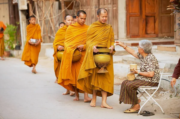 正体不明のシニアのタイの女性が通りチェンマイカーンで タイで午前中に僧侶にもち米を提供するチェンマイカーン 2010 — ストック写真