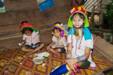 Mae Hong Son, Tayland - 17 Kasım 2008: Kimliği belirsiz bir kadın Lahwi Padaung hill Kabilesinin bir bambu ev Kayan köyde çocuklarda Mae Hong Son, Tayland beslemeleri.