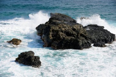 Dalga kırılma sıçramalarına sahilinde aşağı muskaları, Mauritius Adası'nda kayalar.