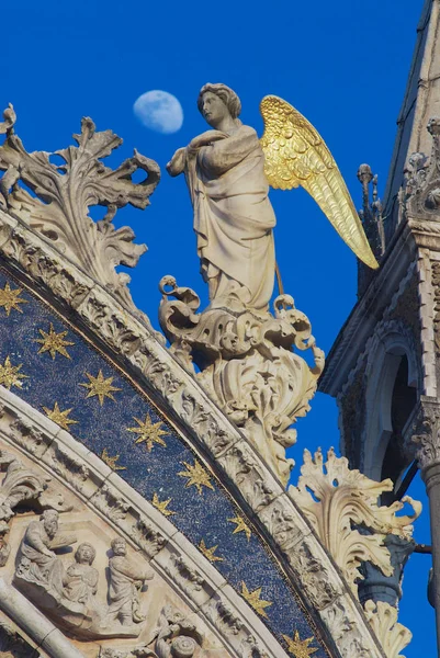 Statue of angel with golden wings decorating upper facade of the Saint Mark's Basilica over the blue evening sky with a moon in Venice, Italy. — Stock Photo, Image