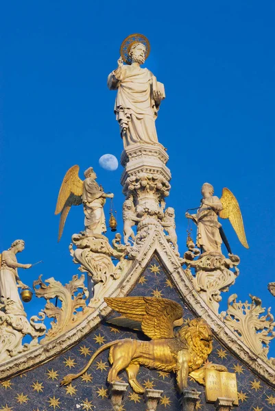 Rzeźby Lwa, aniołów i Jezusa Chrystusa zdobienia górnej fasada Bazyliki Świętego Marka nad niebieski wieczorne niebo, Księżyc w Wenecja, Włochy. — Zdjęcie stockowe