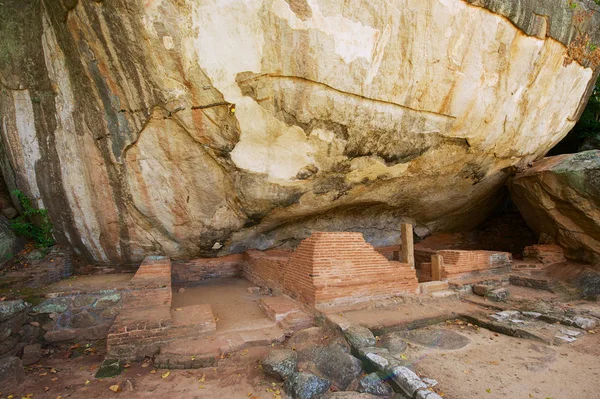 Ancient Buddhist monks meditation caves under big rocks in Sigiriya, Sri Lanka.