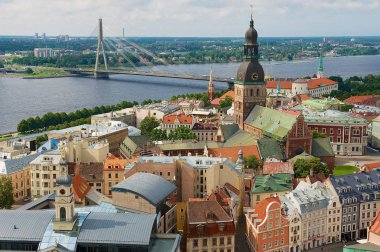 Riga, Letonya - 04 Ağustos 2009: Riga şehrindeki St. Peter kilisesinden eski şehir binalarının ve Daugava nehri karşısındaki köprünün panoraması.