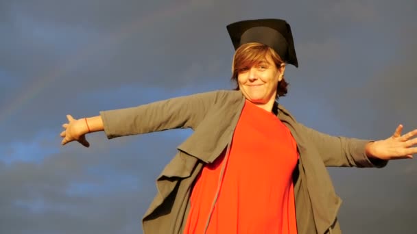 Женщина средних лет танцует со студенческой шляпой на голове в замедленной съемке . — стоковое видео