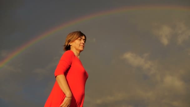 Rainbow - vrouw in rode jurk toont duimen en glimlach. — Stockvideo