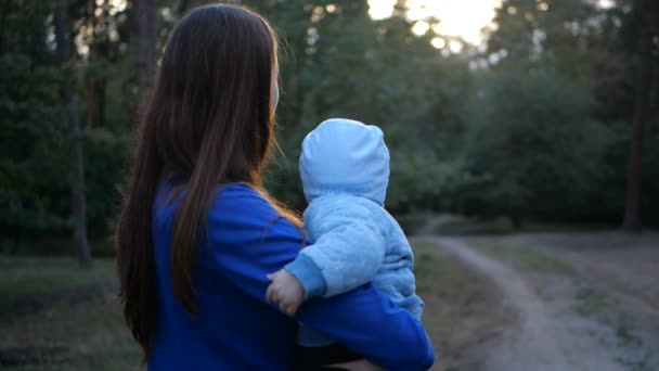 Jeune mère avec enfant sur ses mains debout et regardant sur la route de la forêt . — Video