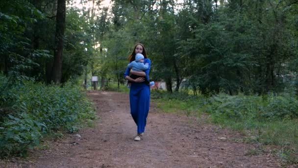 Прогулянка молодою матір'ю і дитиною на руках у лісі повільний рух . — стокове відео