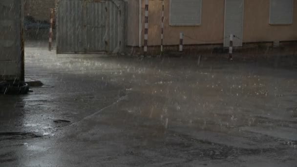 Caen gotas de lluvia sobre el asfalto, disparando cerca del edificio en cámara lenta — Vídeos de Stock