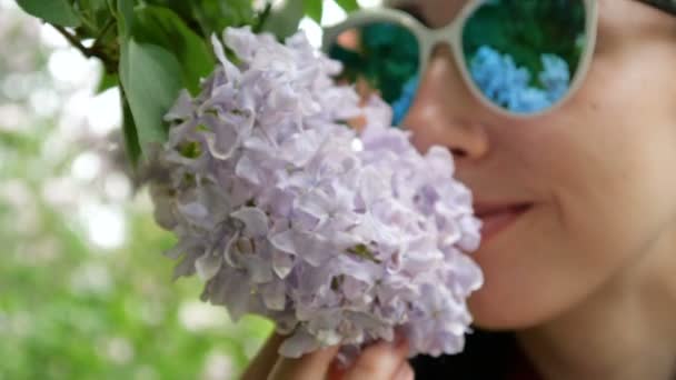 Mädchen mit Sonnenbrille schnuppert Flieder aus nächster Nähe — Stockvideo