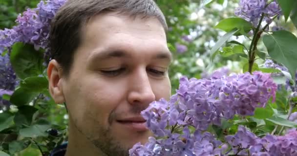 4K - A young guy sniffs lilac and winks in slow motion — Stock Video