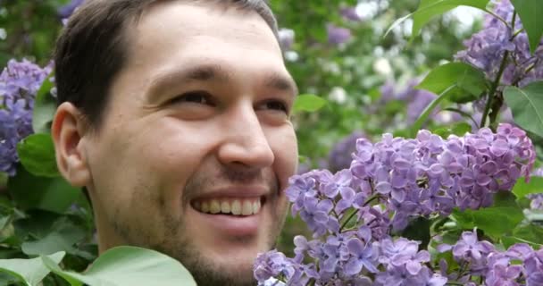 4K - Sonriente tipo oliendo lila en el parque en cámara lenta — Vídeo de stock
