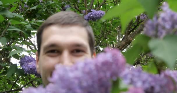 Mann mit hässlichem Gesicht lächelt in Flieder - 4k. — Stockvideo