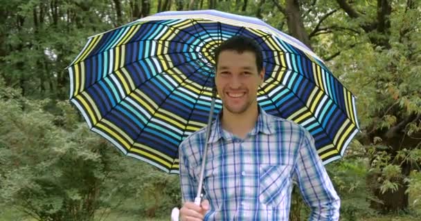 4k - мужчина с зонтиком, стоящий в саду и улыбающийся . — стоковое видео