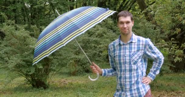 Man with funny face open umbrella in the garden. — Stock Video