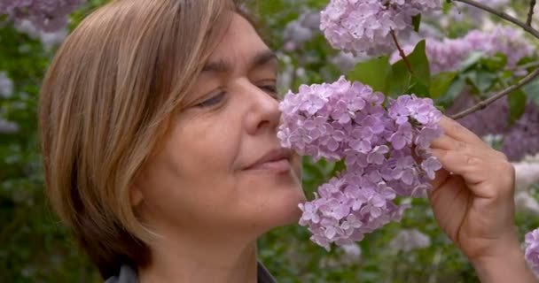 Frau mittleren Alters mit Blumen in der Hand - flieder. — Stockvideo