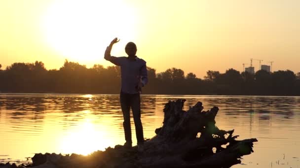 Blond człowiek w słuchawki tańce, podnosi ręce o zachodzie słońca w slo-mo — Wideo stockowe