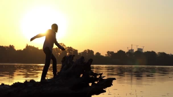 O homem do disco salta em um banco de lago em um por do sol dourado — Vídeo de Stock