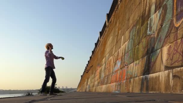 Sportieve man gooit een bal op een rivier bank muur in slo-mo — Stockvideo