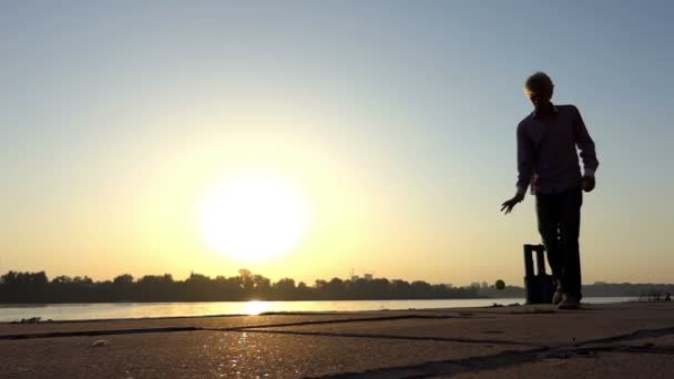 Šťastný muž kapky míč na břehu řeky při západu slunce v slo-mo — Stock video