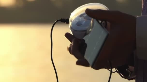 Torcia in vetro e batteria solare sono tenuti al tramonto — Video Stock