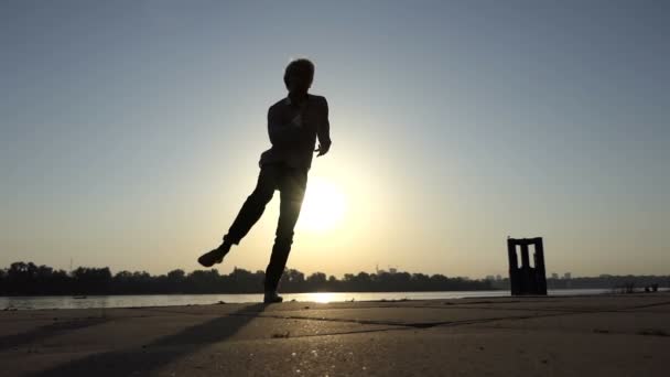 Jonge man dansen disco actief aan de rivieroever van een in slo-mo — Stockvideo