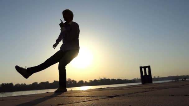 El hombre alegre baila activamente en la orilla del río en verano en slo-mo — Vídeos de Stock