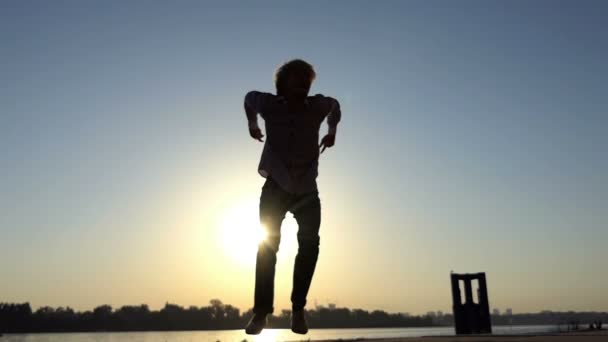 Щасливий чоловік танцює диско на березі річки влітку в шлю-мо — стокове відео