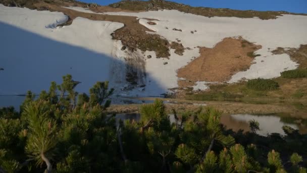 Крутой склон со снегом и небольшим озером у подножия Карпат в сло-мо — стоковое видео