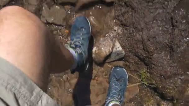 Håriga manliga ben i Snickers går i ett berg Rill med stenar i slow motion — Stockvideo