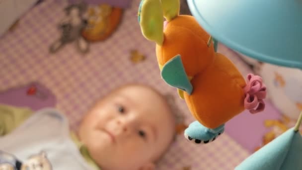 Newborn baby lays on his bed and looking on the toys. — Stock Video