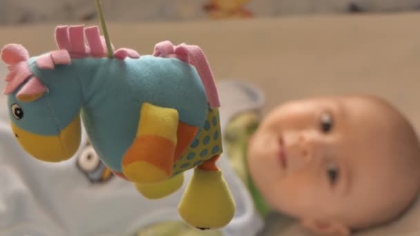 Newborn baby lays on his bed and looking on the toys. — Stock Video
