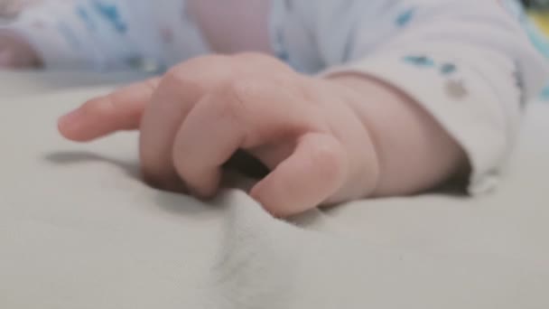 Kleine hand van een kleine baby liggend op een bed en friemelen — Stockvideo