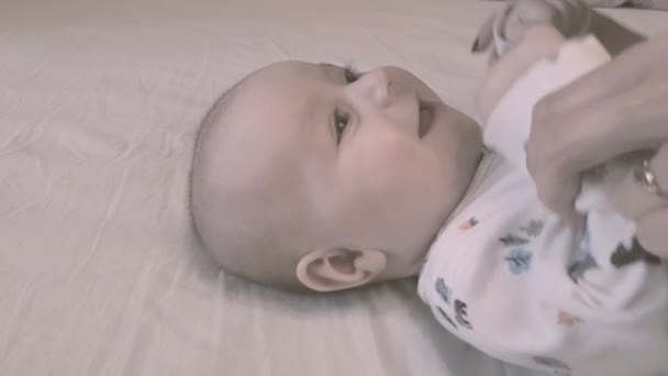 Un niño de un año acostado y sonriendo felizmente en una cama inddors — Vídeos de Stock