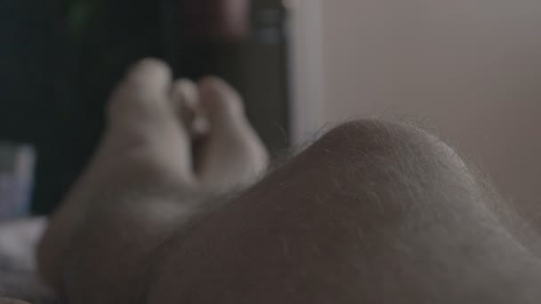 4k slow motion-mans håriga ben ligger på soffan — Stockvideo