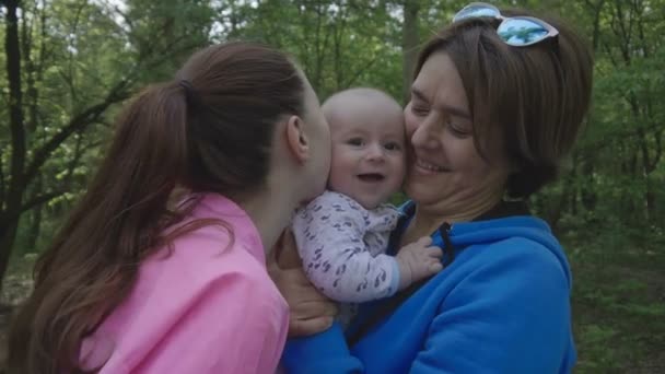 Família feliz na floresta mãe beija seu bebê e avó feliz . — Vídeo de Stock