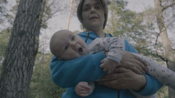 Grandmother and kid on her hands in the forest. — Stock Video