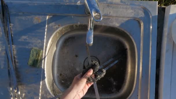 Las manos femeninas lavando brochetas metálicas largas sobre un fregadero de cocina de jardín en slo-mo — Vídeos de Stock