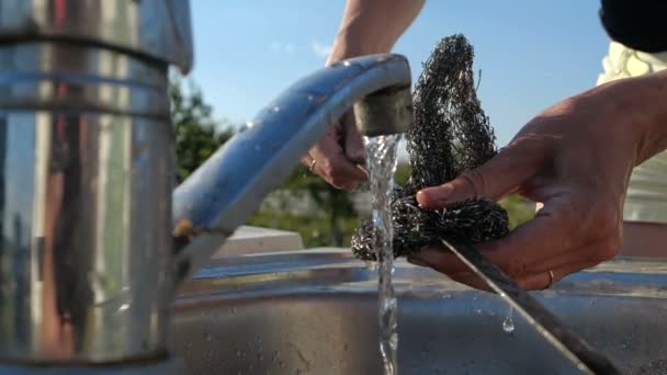 Young woman s hands scouring a long skewer over outdoor sink in summer in slo-mo — Stock Video