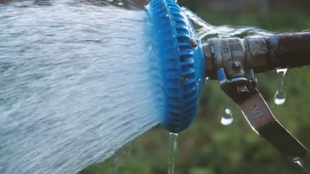 Sprankelende water stroomt van een douchekop in een tuin in de zomer in slow motion — Stockvideo
