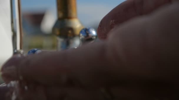Жіночі руки миють один одного на металевому крані в саду влітку в шлю-мо — стокове відео