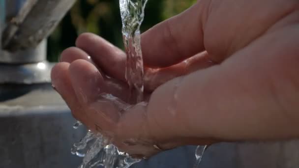 Fe,ale hands under a stream of clean water outdoors among greenery in slo-mo — Stock Video