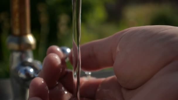 Жінка руки під струмком води в саду влітку в повільному русі — стокове відео