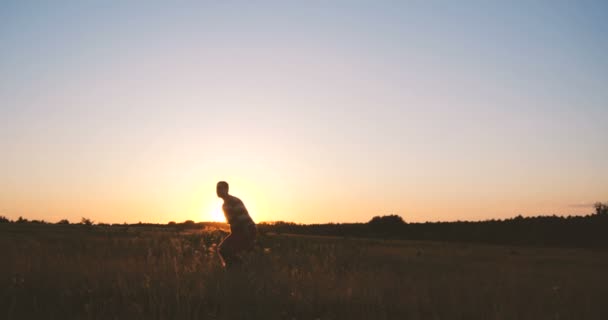 Glücklicher junger Mann springt und hebt im Sonnenuntergang in Zeitlupe die Hände — Stockvideo
