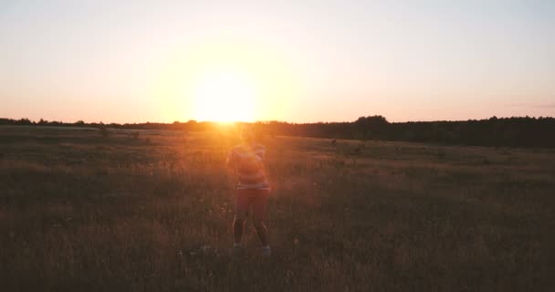 Jovem alegre pulando alto como um palhaço e sorrindo ao pôr do sol em slo-mo — Vídeo de Stock