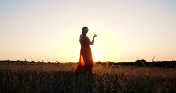 Красивая женщина средних лет танцует в поле на закате в замедленной съемке — стоковое видео