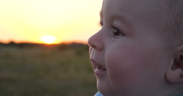 Annesine bakarak ve bir alanda slo-mo gün batımında gülümseyen mutlu bebek — Stok video