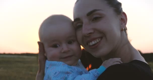 Оптимистичные мать и ее ребенок в руках обнимают друг друга на закате в slo-mo — стоковое видео