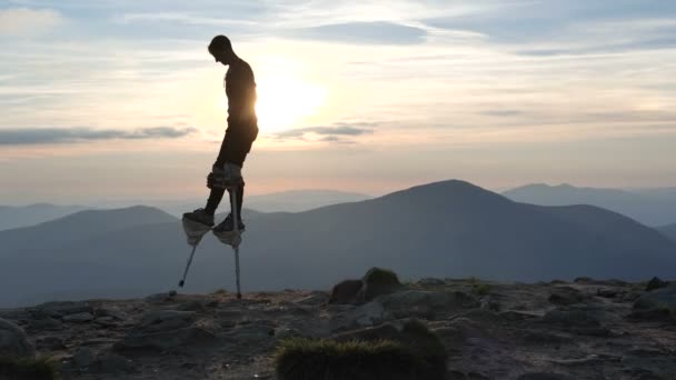 El hombre en los zancos camina en la cima de la montaña al atardecer . — Vídeo de stock